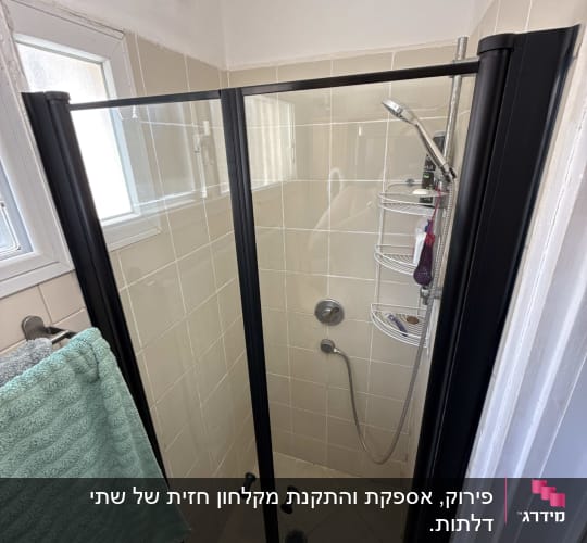 מקלחת עם דלת זכוכית, ראש מקלחת ומגבת תלויה